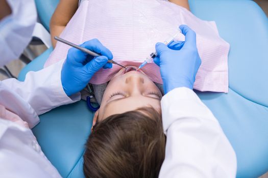 High angle view of dentist holding medical equipment while examining boy at clinic