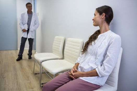 Woman looking at dentist while sitting on chair at waiting room