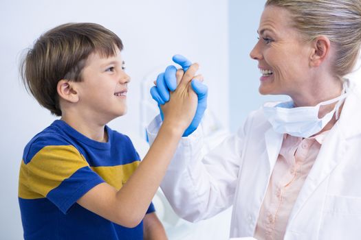 Smiling dentist playing with boy at medical clinic