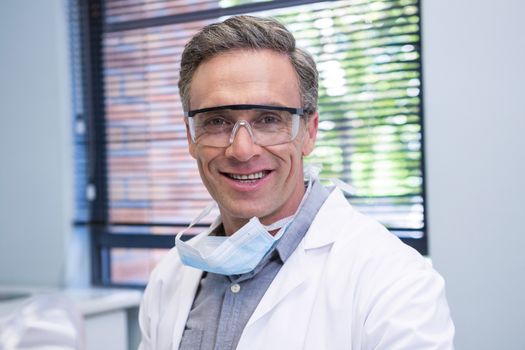 Portrait of smiling dentist standing against window at medical clinic