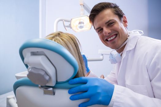 Portrait of happy dentist examining woman at medical clinic