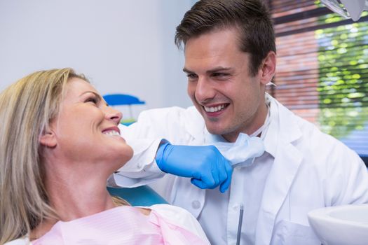 Cheerful patient looking at dentist while sitting on chair at dental clinic