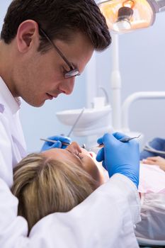 Close up dentist examining woman with dental equipments at medical clinic