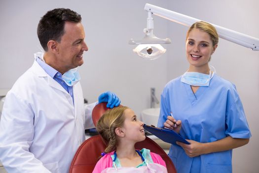 Dentist and young patient looking at nurse in clinic