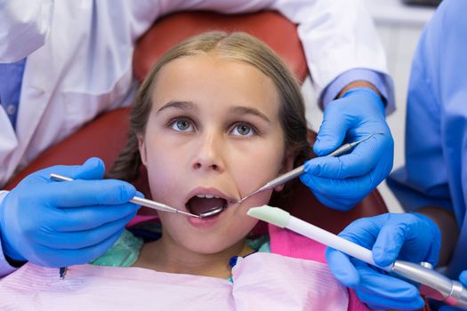 Mid section of dentist and nurse examining a young patient with tools in clinic