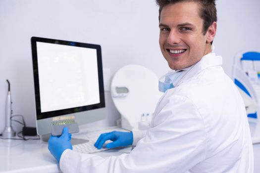 Portrait of dentist working on computer against wall at medical clinic