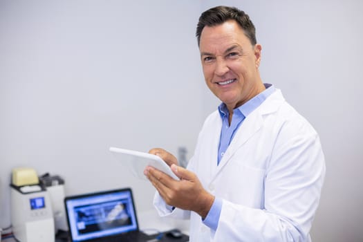 Portrait of happy dentist using digital tablet in clinic