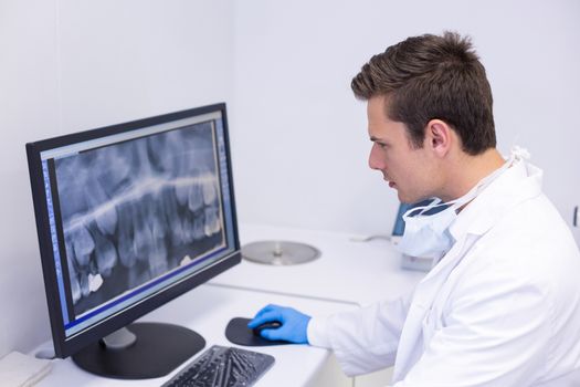 Attentive dentist examining x-ray report on computer in clinic