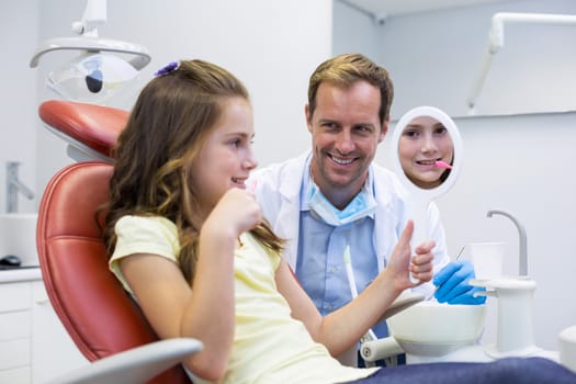 Smiling young patient looking in the mirror with a dentist in dental clinic