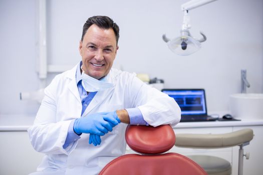 Portrait of smiling dentist sitting in dental clinic