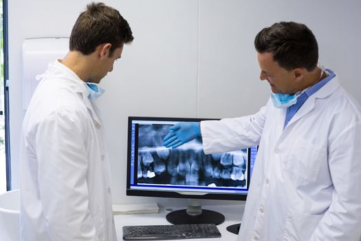Dentist examining x-ray report on computer in clinic