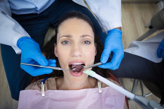 Dentist examining a female patient with tools at dental clinic