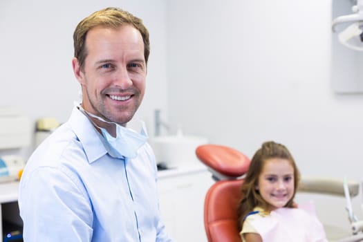 Portrait of smiling dentist and young patient in dental clinic