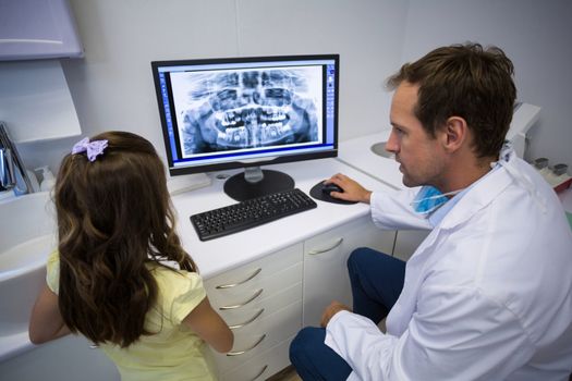 Dentist showing x-ray on computer to young patient in dental clinic