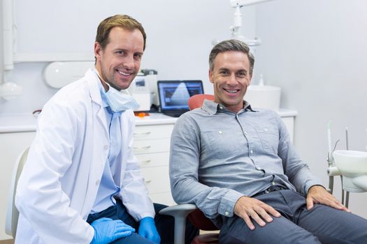 Portrait of smiling dentist and patient in dental clinic
