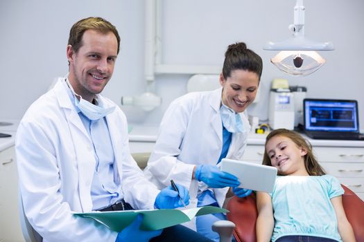 Dentist showing digital tablet to young patient in dental clinic