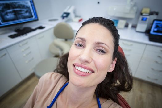 Portrait of smiling female patient sitting on dentist chair at dental clinic