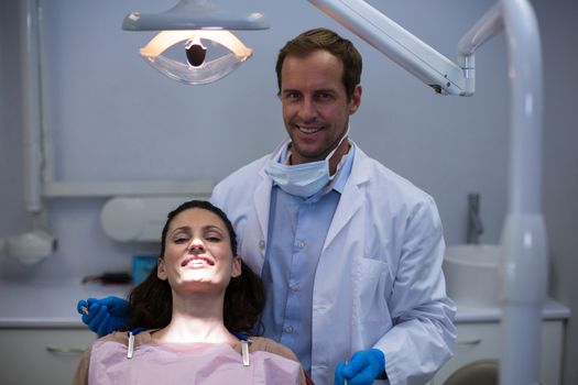 Portrait of smiling dentists and female patient at dentist clinic