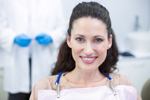 Portrait of smiling female patient sitting on dentist chair at dental clinic