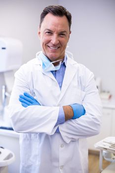 Portrait of smiling dentist standing with arms crossed at dental clinic