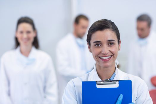 Portrait of smiling dentist standing at dental clinic