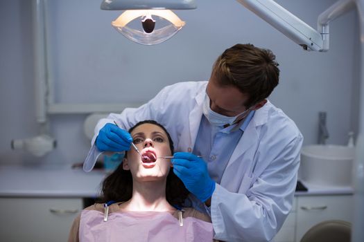 Dentist examining a female patient with tools at dental clinic