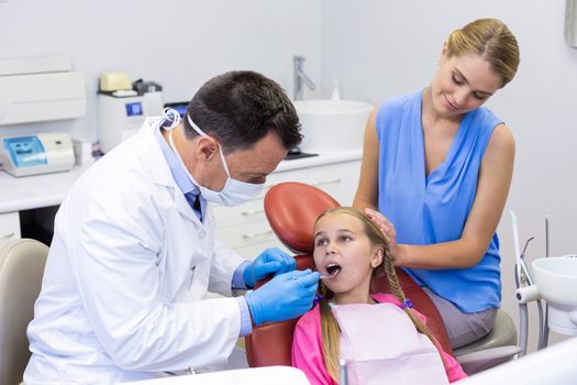 Dentist examining a young patient with tools at dental clinic