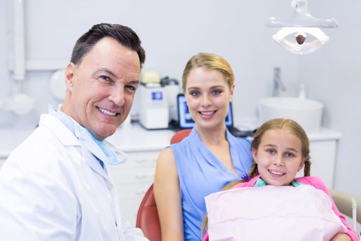 Portrait of dentist with young patient and his mother at dental clinic