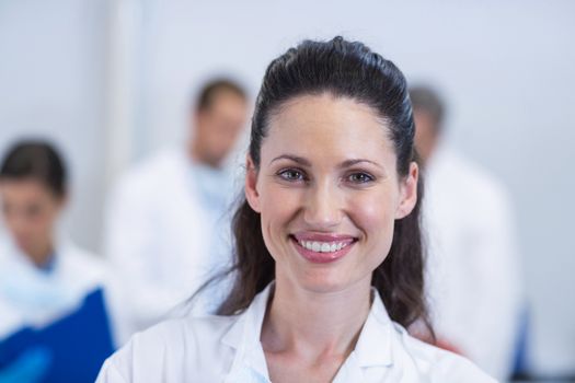 Portrait of smiling dentist standing at dental clinic