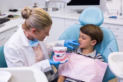 High angle view of dentist holding dental mold while examining boy at clinic