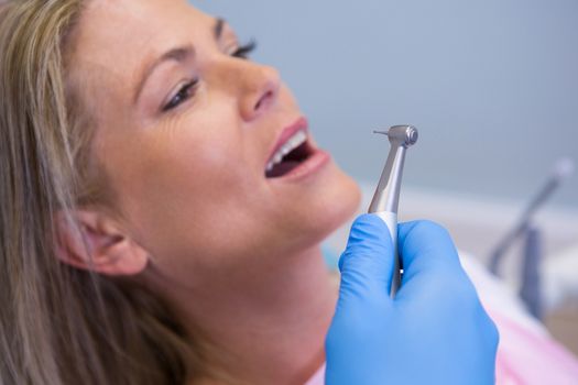 Cropped image of dentist holding medical equipment while giving treatment to patient at clinic