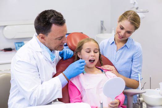 Dentist examining a young patient with tools at dental clinic
