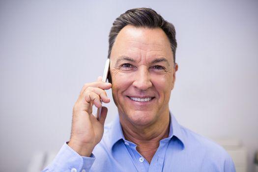 Portrait of dentist talking on mobile phone at dental clinic