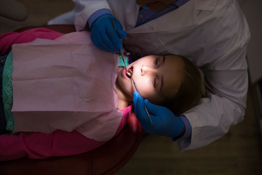 Dentist examining a young patient with tools at dental clinic