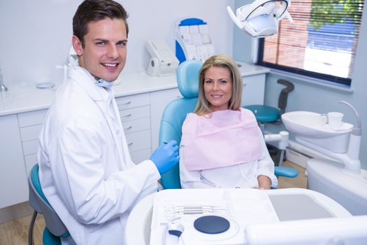 Portrait of smiling patient and dentist sitting at dental clinic