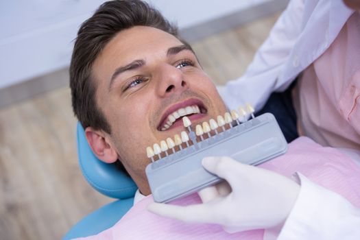 High angle view of dentist holding equipment while examining man at medical clinic