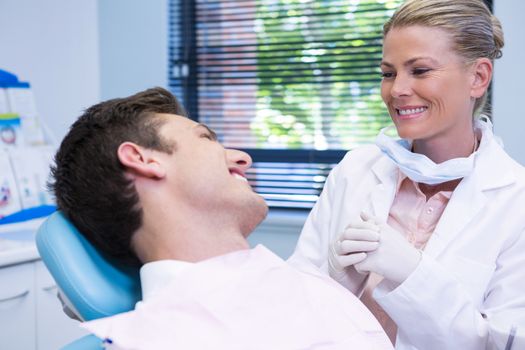 Happy patient looking at dentist while sitting on chair in medical clinic