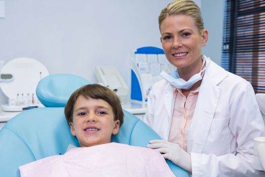 Portrait of boy sitting on chair by dentist at clinic