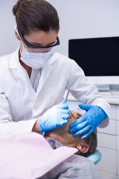 Man receiving dental treatment by dentist at medical clinic