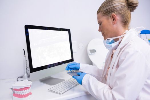 Side view of dentist working while sitting by computer at clinic