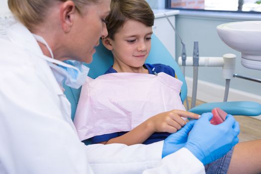 Dentist and boy looking at dentures at medical clinic