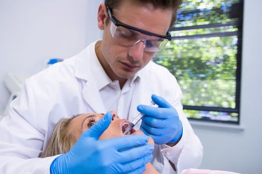 Close up of dentist giving anesthetic to woman at medical clinic