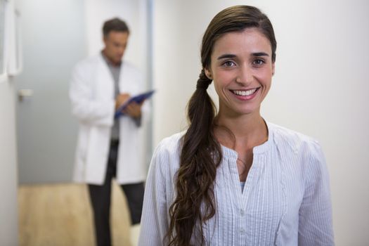 Portrait of smiling woman against dentist standing in lobby at medical clinic