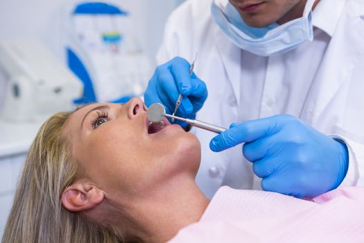 Close up of dentist examining young woman at medical clinic
