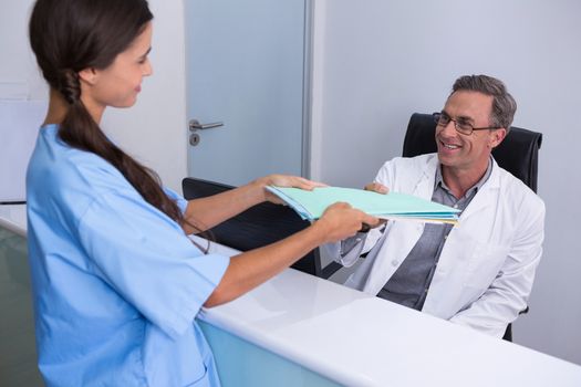 Patient giving files to dentist at medical clinic
