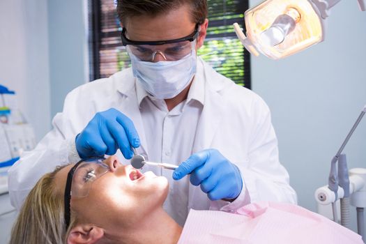 Dentist holding tools while examining woman at medical clinic