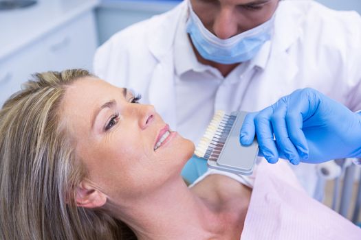 High angle view of dentist holding equipment while examining patient at medical clinic