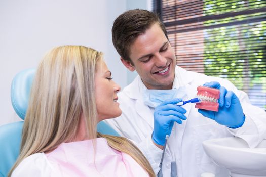 Dentist showing dental mold to patient at medical clinic
