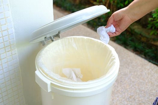 Background with The hand holding the tissue paper for tipping into the trash in the bathroom.  Disposing waste in trash. 