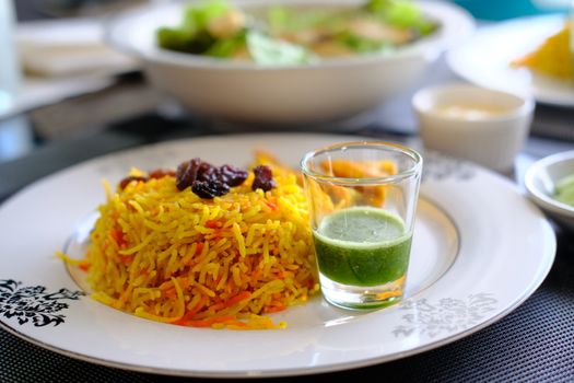 Prawn Biryani served with fried shrimp, green pepper sauce and raisins. Delicious Indian seafood traditional cuisine. 